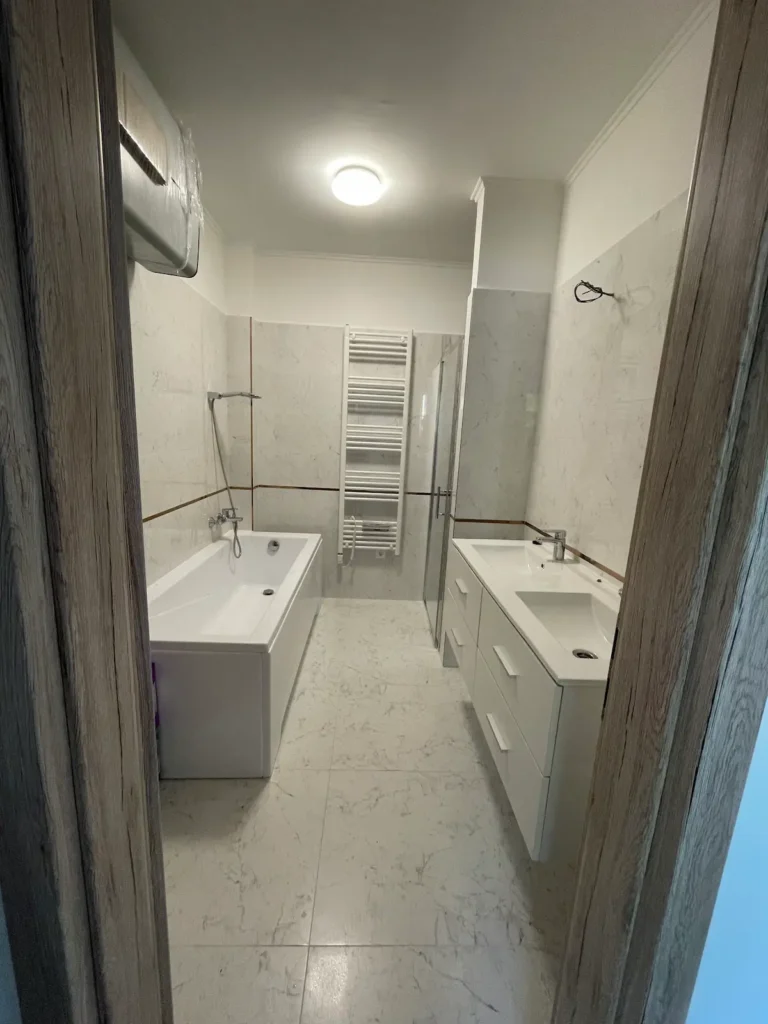 Berendezett fürdőszoba, káddal, fehér színű mintás burkolattal