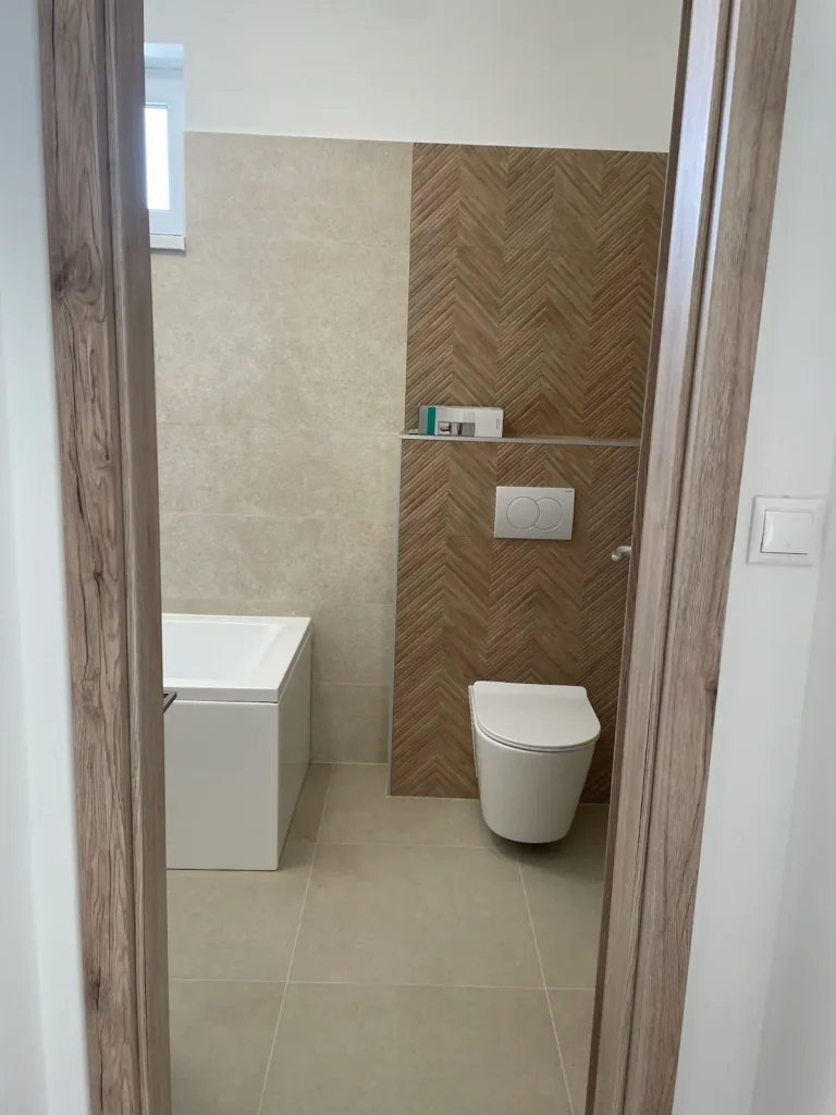 Fürdőszoba és illemhely bejárati része, modern megjelenésű burkolattal