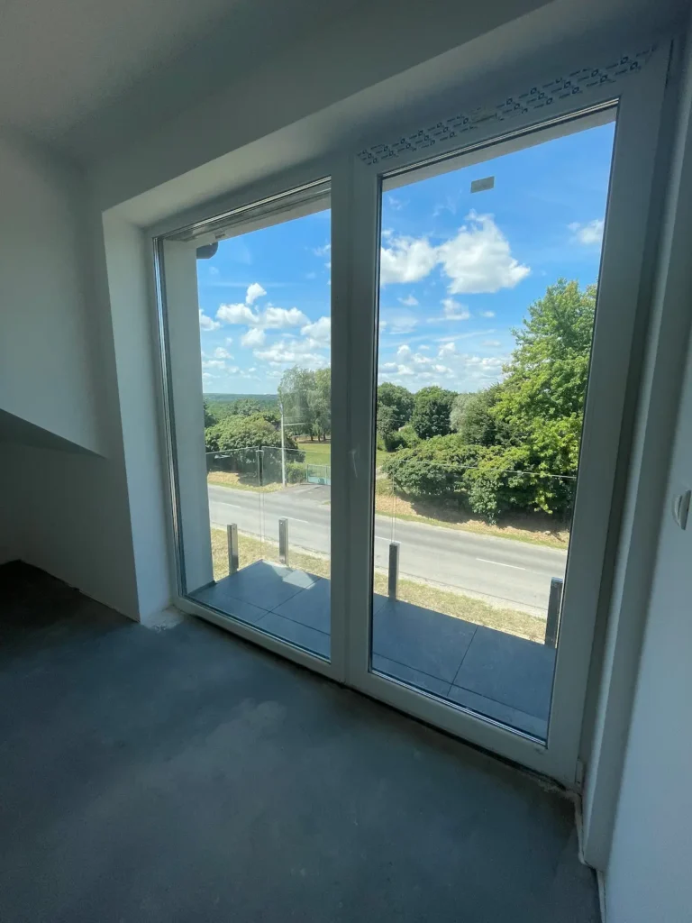 Szobából erkélynézet az üveges ajtókon keresztül a kinti fás környezetre